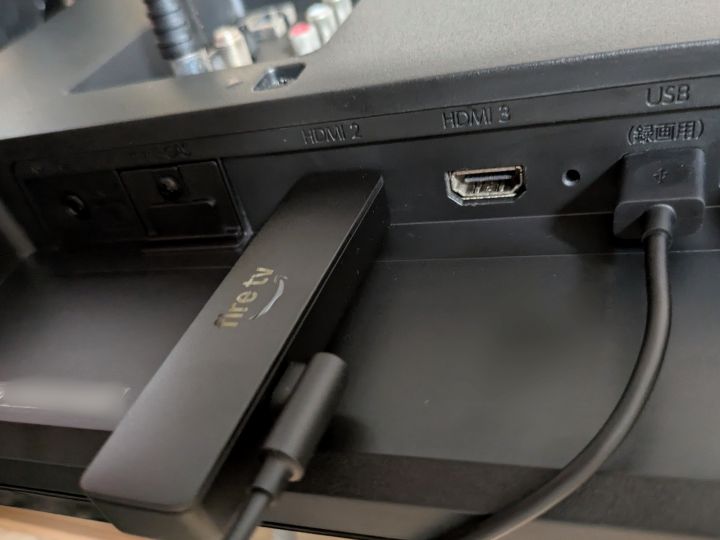 テレビのHDMI端子に接続されたFire TV Stickと、本体側面からテレビのUSBポートへ繋がれた電源ケーブルの実物写真