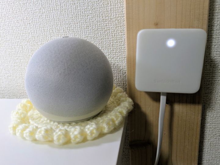 棚の上に置いた白いEcho Dotと壁掛けしたSwitchBotハブミニ